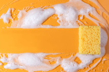 Sabunla temizlik süngeri. Sarı arka planda köpük köpüklü doku. kopyalama alanı. Süngerle temizlik..