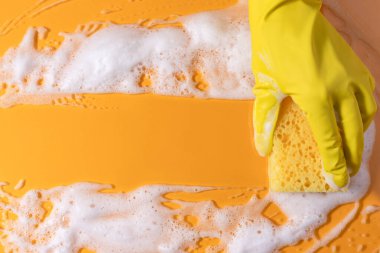 Sabunla temizlik süngeri. Sarı arka planda köpük köpüklü doku. kopyalama alanı. Süngerle temizlik..