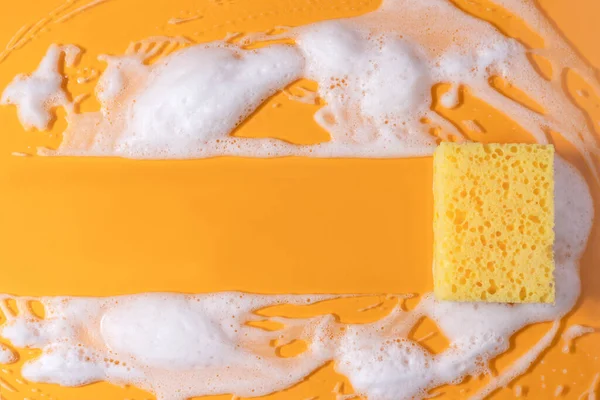 Sabunla temizlik süngeri. Sarı arka planda köpük köpüklü doku. kopyalama alanı. Süngerle temizlik..