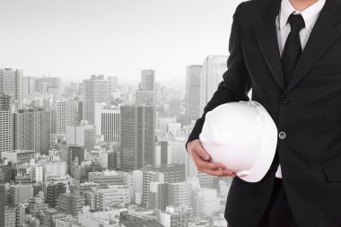 Şehir arka plan beyaz kask tutan mühendisi