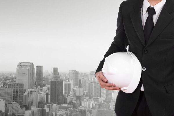 engineer holding white helmet with city background