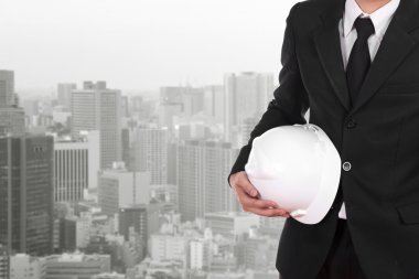 Şehir arka plan beyaz kask tutan mühendisi