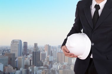 Şehir arka plan beyaz kask tutan mühendisi