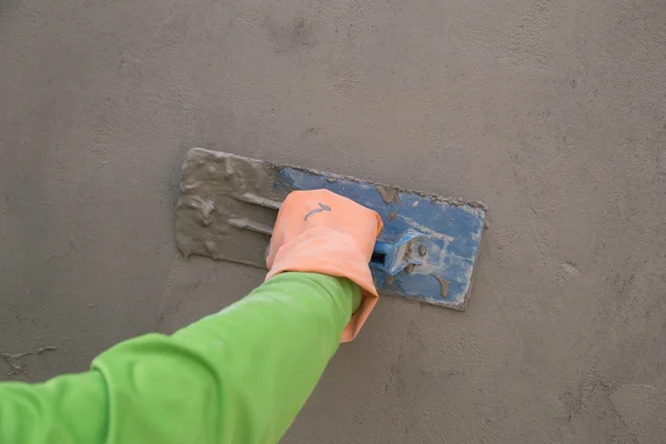 Mano con spatola per finire muro di cemento bagnato alla costruzione si — Foto Stock