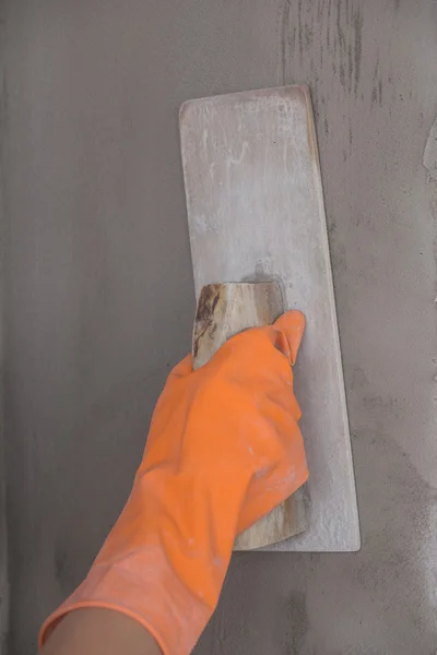 Mano del lavoratore uso spatola intonaco calcestruzzo a parete — Foto Stock