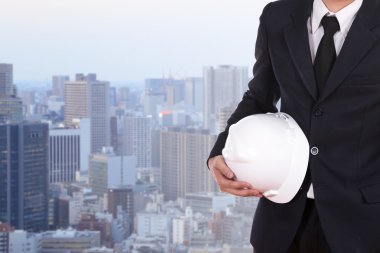 Şehir arka plan beyaz kask tutan mühendisi