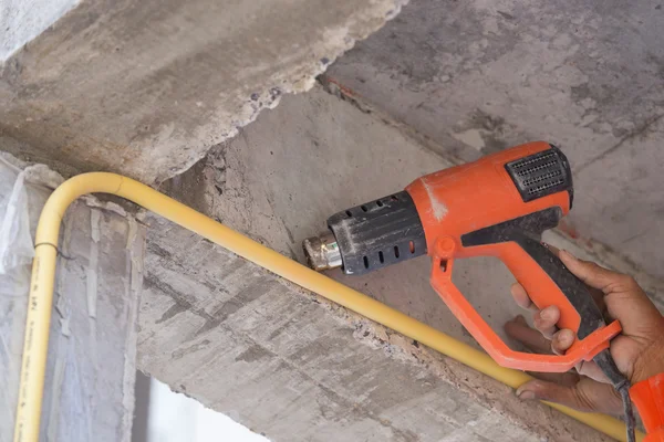 Hand use a heat gun to bending electric PVC pipe — Stock Photo, Image