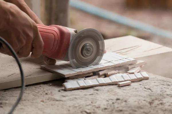 Travailleur de la construction couper une tuile à l'aide d'une meuleuse d'angle — Photo