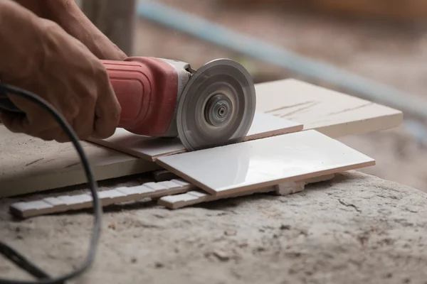 Travailleur de la construction couper une tuile à l'aide d'une meuleuse d'angle — Photo