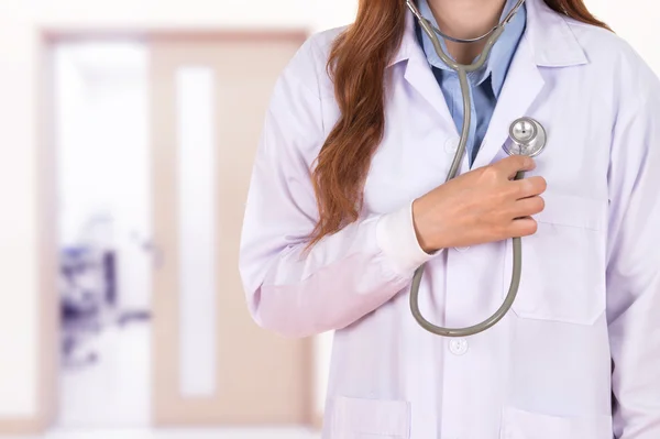 Kobieta lekarz słucha jego serca z stetoskop w szpitalu — Zdjęcie stockowe