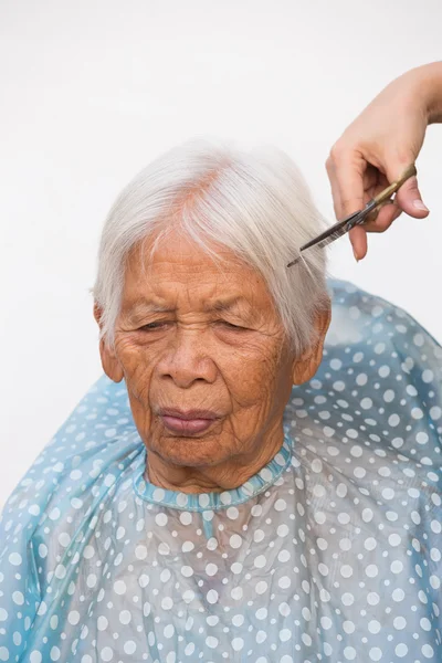Cutting senior woman's gray hair — Stock Photo, Image
