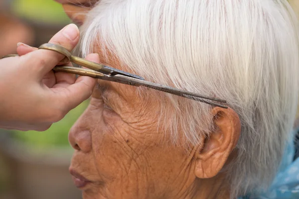 Die grauen Haare der Seniorin schneiden — Stockfoto