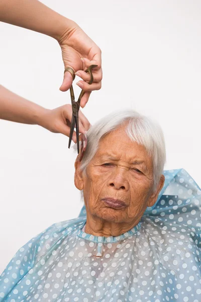 Cutting senior woman's gray hair — Stock Photo, Image