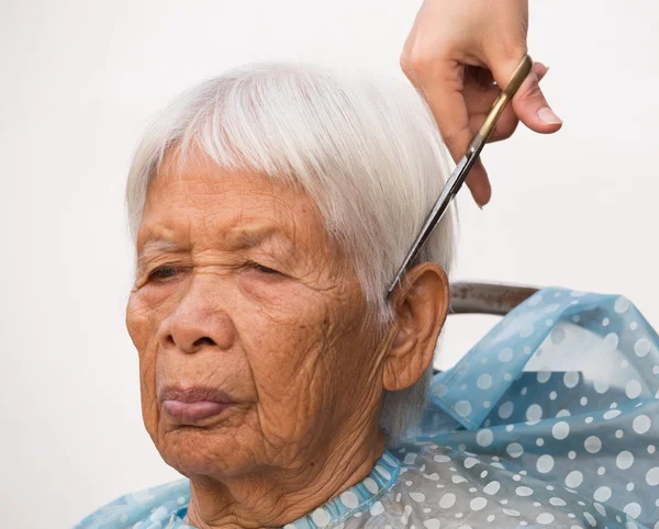 Cutting senior woman's gray hair — Stock Photo, Image