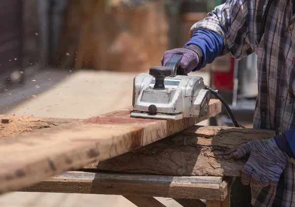 Operaio che pialla un legno con un piano elettrico — Foto Stock
