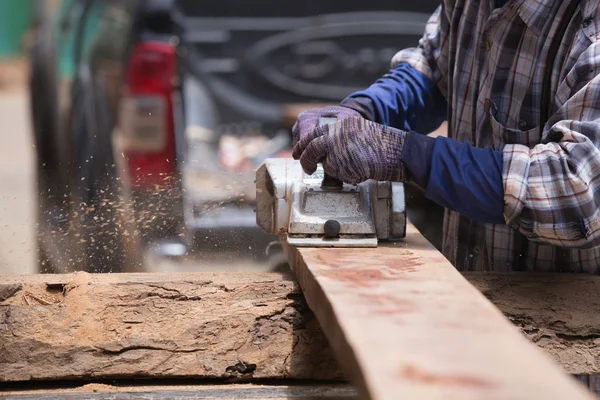 Trabajador cepillando una madera con un plano eléctrico — Foto de Stock