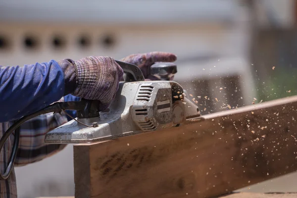 Trabajador cepillando una madera con un plano eléctrico — Foto de Stock