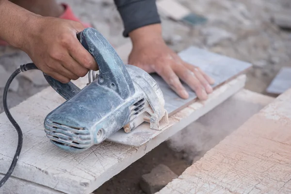 Arbeiter schneidet eine Fliese mit einem Winkelschleifer — Stockfoto