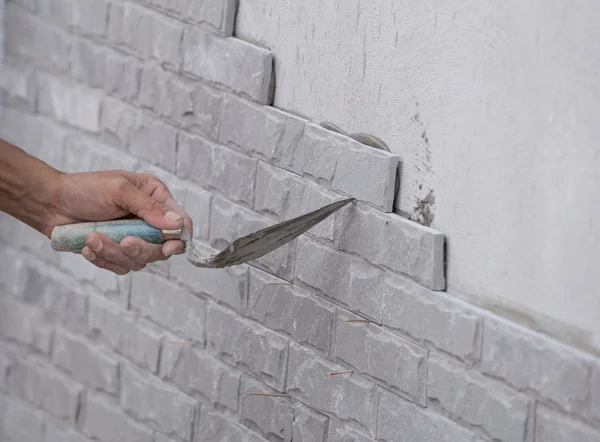 Рабочий устанавливает поверхность каменной стены с цементом для дома — стоковое фото
