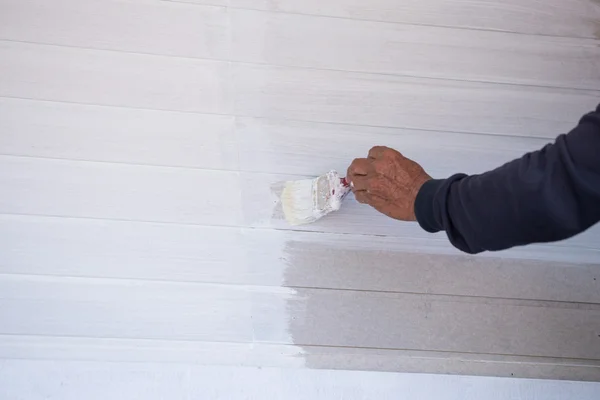 Hand holding brush painting timber wall — Stock Photo, Image