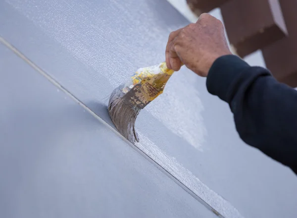 Mão segurando parede pintura escova — Fotografia de Stock