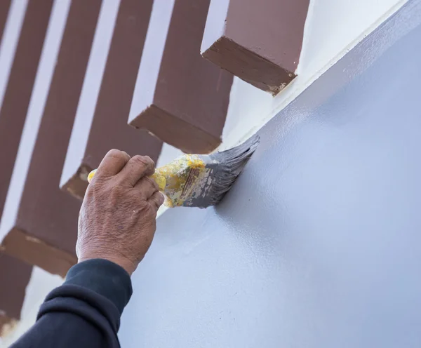 Mão segurando parede pintura escova — Fotografia de Stock