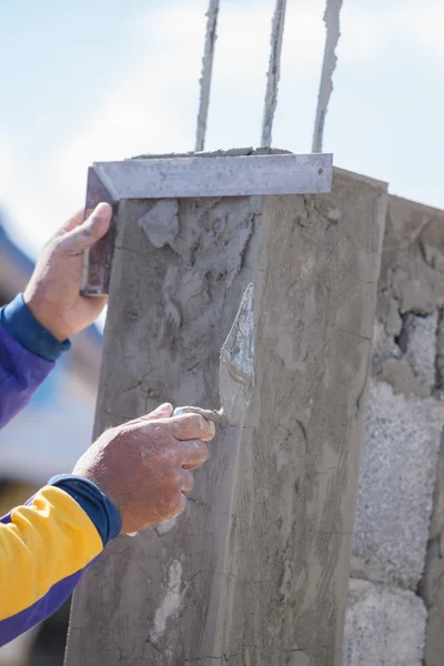 Trabajador utilizar regla de hierro snd llana enlucido de los postes — Foto de Stock