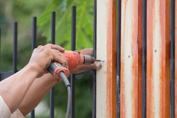 Mains utilisant perceuse électrique sur bois de clôture — Photo