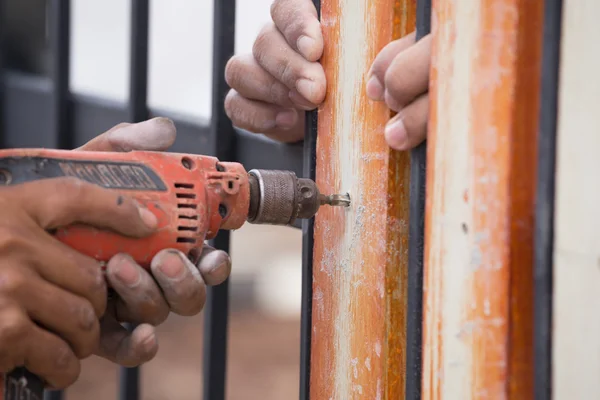 Hands using electric drill on fence wood — Stock Photo, Image