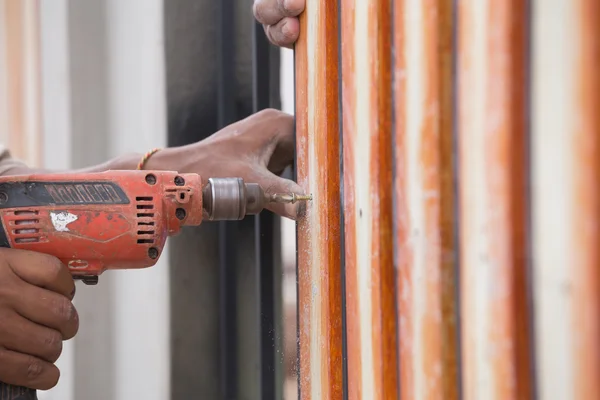 Hands using electric drill on fence wood — Stock Photo, Image