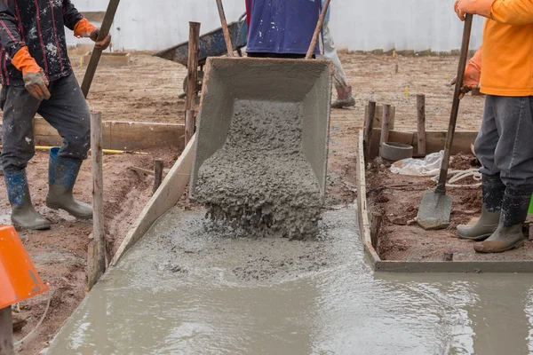 Worker pouring cement from cart to floor — Stock Photo, Image