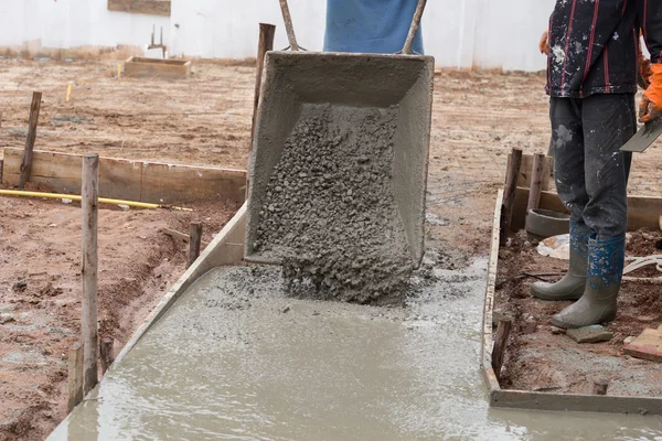 Trabajador vertiendo cemento de carro a piso —  Fotos de Stock
