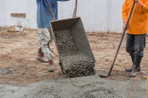 Trabajador vertiendo cemento de carro a piso — Foto de Stock