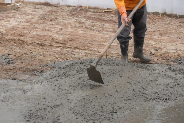 Arbetstagaren använder hoe på en nyligen hällde betonggolvet — Stockfoto