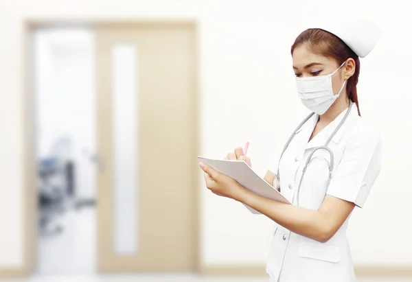 Nurse with stethoscope writing medical report in hospital — Stock Photo, Image