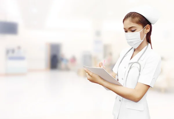 Nurse with stethoscope writing medical report in hospital — Stock Photo, Image