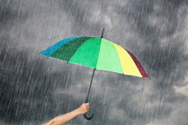 çok renkli şemsiye yağmur ile karanlık gökyüzü altında tutan el