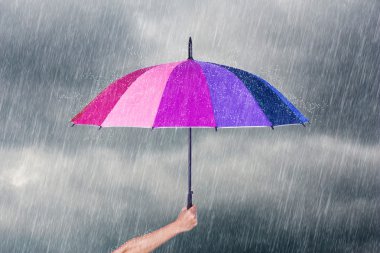 çok renkli şemsiye yağmur ile karanlık gökyüzü altında tutan el