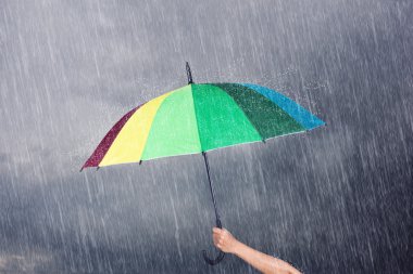 çok renkli şemsiye yağmur ile karanlık gökyüzü altında tutan el