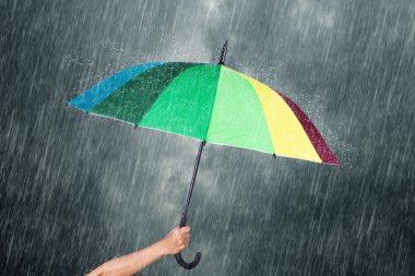 çok renkli şemsiye yağmur ile karanlık gökyüzü altında tutan el