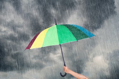 çok renkli şemsiye yağmur ile karanlık gökyüzü altında tutan el