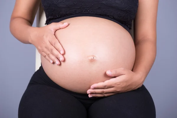 Close-up da barriga da mulher grávida com a mão — Fotografia de Stock