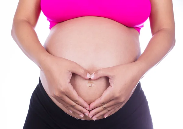 Ventre enceinte de la femme avec les doigts Forme de coeur sur le dos blanc — Photo