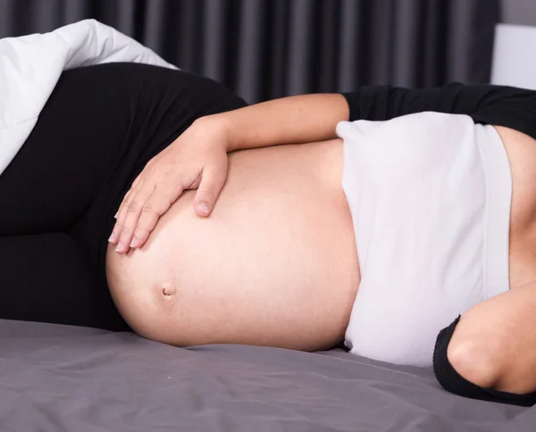Göbek yatak yatak odasında uyuyan hamile kadın kapatmak — Stok fotoğraf