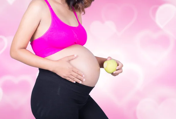 Mulher grávida bonita com maçã no fundo do coração — Fotografia de Stock