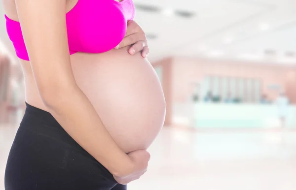 Close-up de barriga de mulher grávida com a mão sobre ele no hospital — Fotografia de Stock