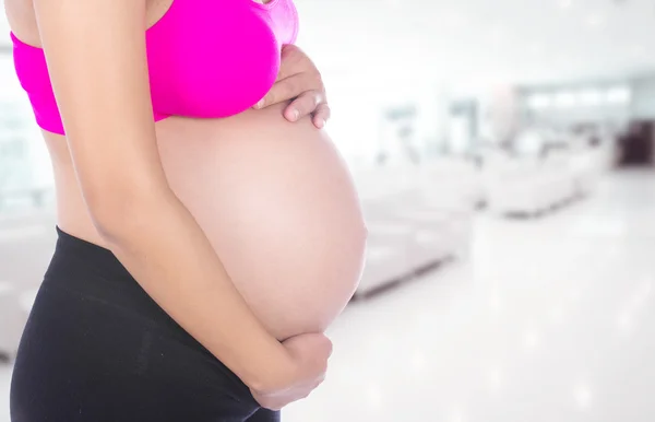 Gros plan du ventre de la femme enceinte avec sa main dessus à l'hôpital — Photo