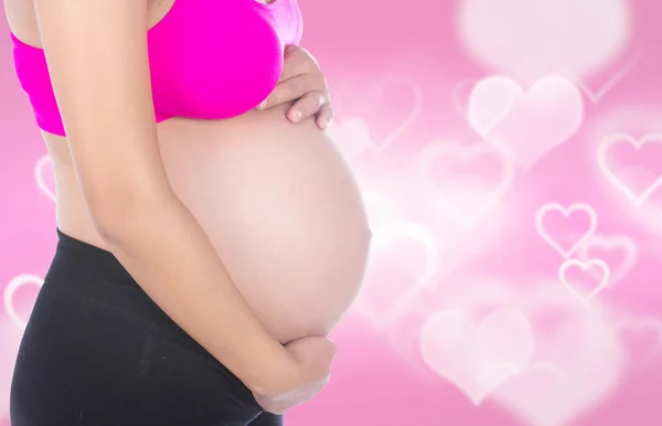 Primo piano della pancia donna incinta con la mano su di esso sul cuore ba — Foto Stock