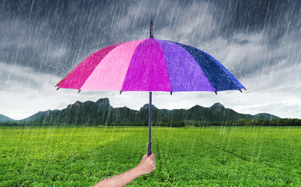 Χέρι εκμετάλλευση πολύχρωμη ομπρέλα με βροχή που πέφτει στο Jee Καο — Φωτογραφία Αρχείου