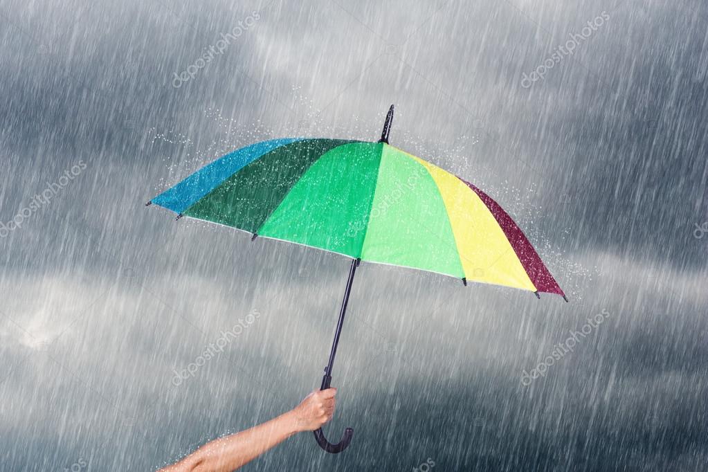 Main tenant parapluie  multicolore sous le ciel sombre avec 